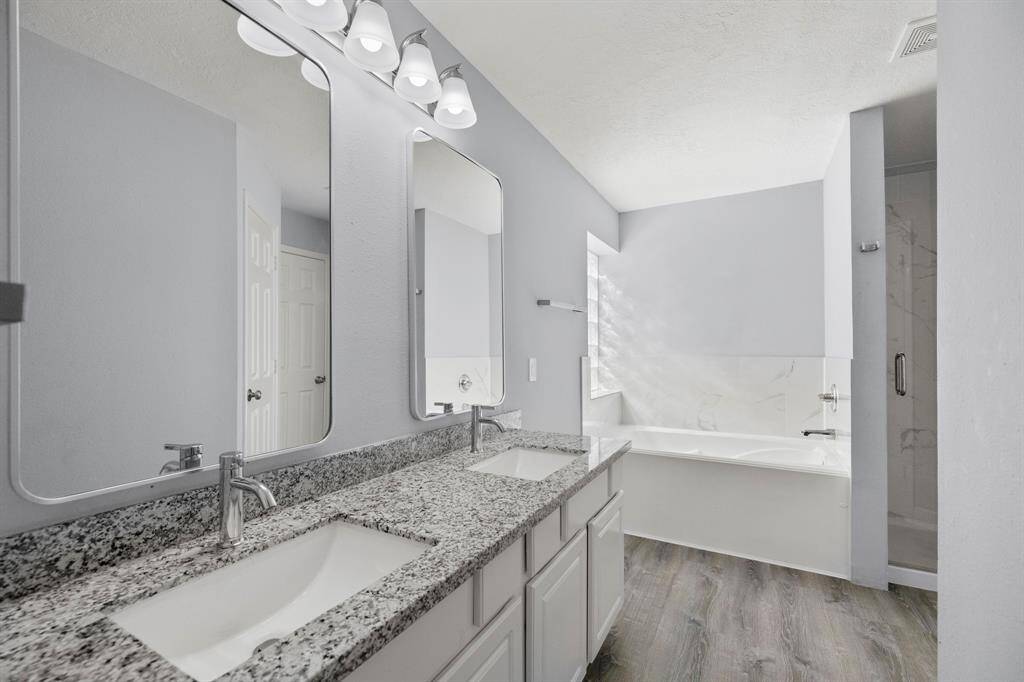 The master bathroom features double sinks with vanities across from each other as seen here. The sleek white vanities allow the chrome hardware, faucets, & matching light fixtures to beautifully stand out.