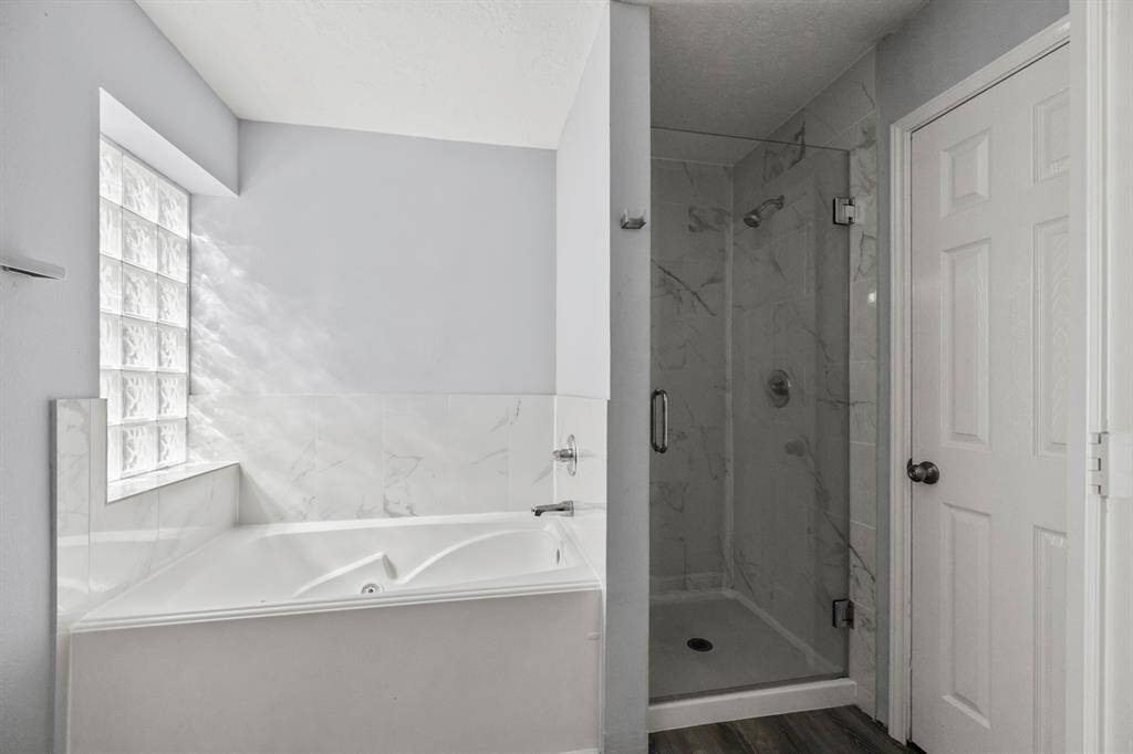 Come check out your luxurious master bathroom! Sleek grey & white tile flows from the floor to surround the large soaking bathtub & walk-in standing shower. The doors to the right are to the toilet & walk-in closet.
