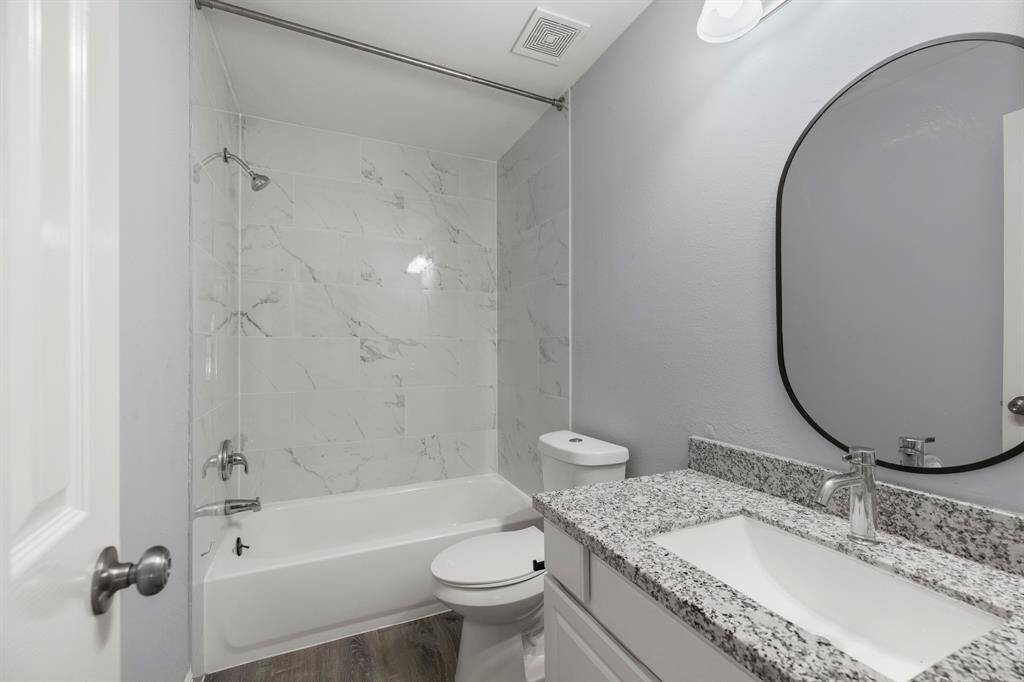 On the second floor youll find the full secondary bathroom. It features gorgeous sleek white vanity with chrome hardware & a shower/tub combo lined in large grey tiles.