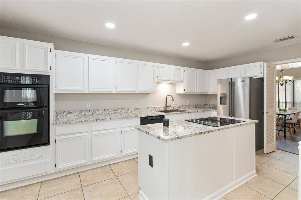 The kitchen offers a cooking island, microwave/oven combination, dishwasher, and stainless refrigerator.
