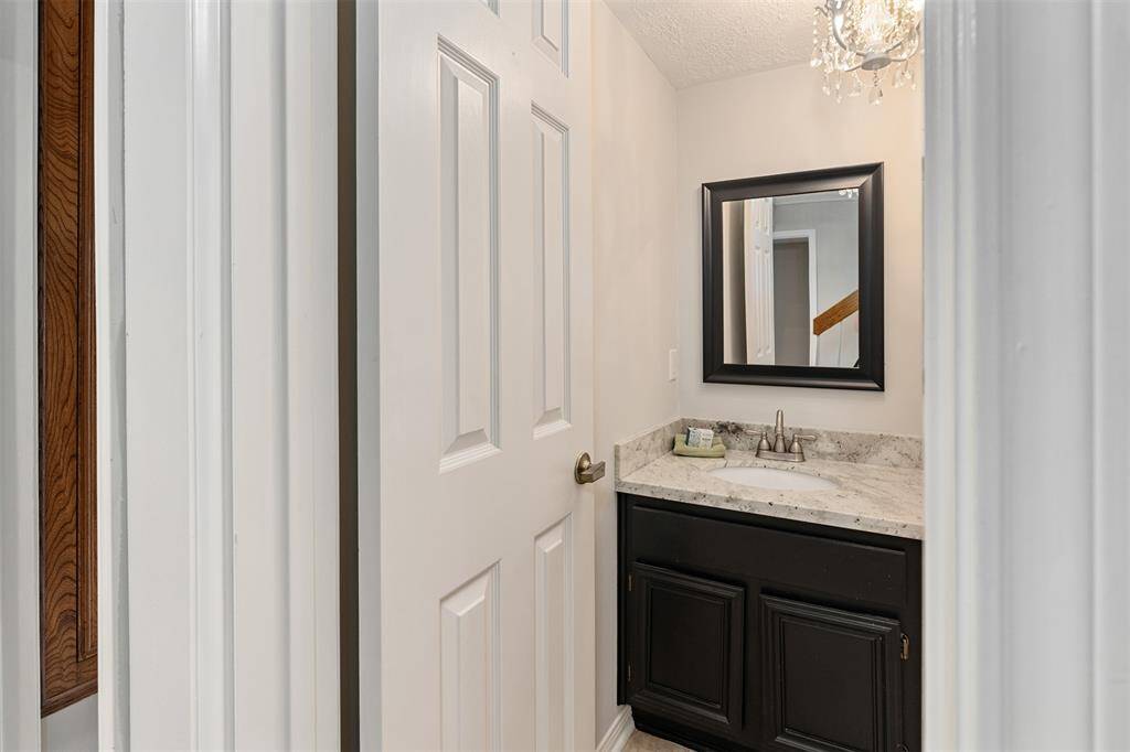 The powder room is located in the entry area and boasts a granite countertop and a sparkling chandelier.