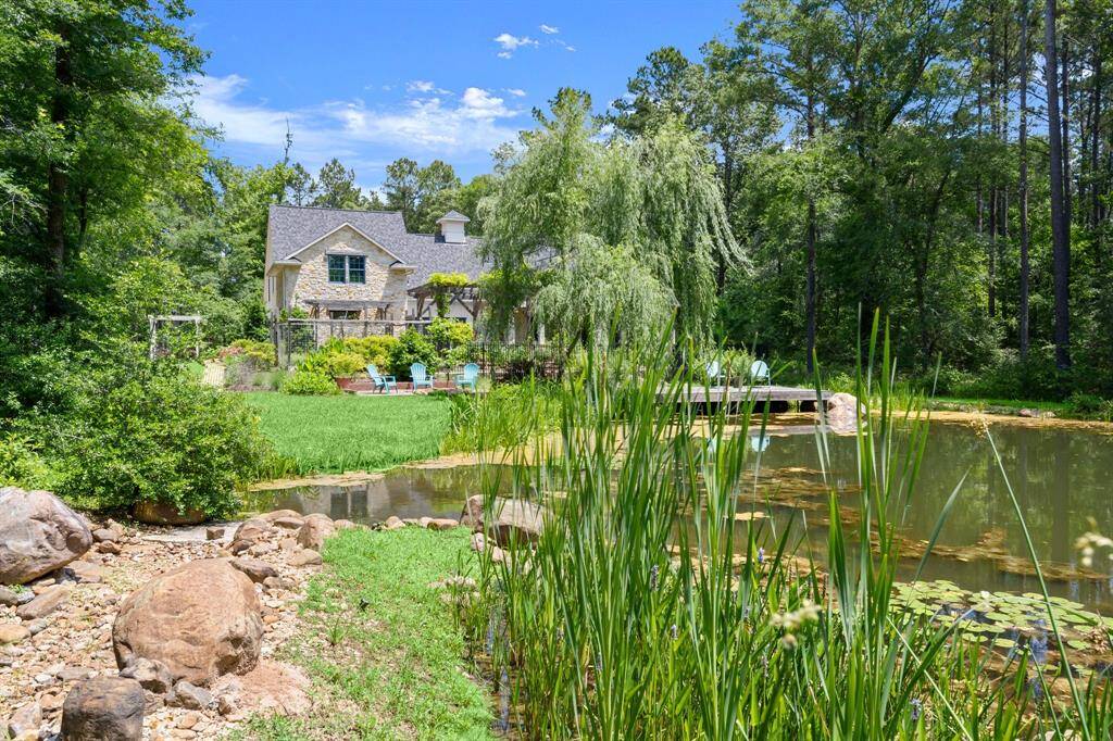 This serene property features a charming house surrounded by lush greenery and a tranquil pond with lily pads. Ideal for nature lovers, the scene offers a peaceful retreat with ample privacy and scenic views.