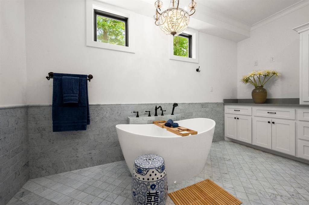 A sleek, modern freestanding tub sits adjacent to the vanity, offering a spa-like feel. The design is complemented by a dark bronze faucet system, adding a touch of contrast and timelessness.