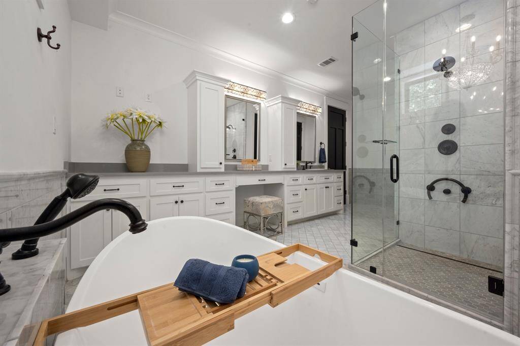 The glass-enclosed shower features a frameless door and full-length panels for a clean and open appearance. The use of clear glass maximizes the visibility of the luxurious tile work within the shower.