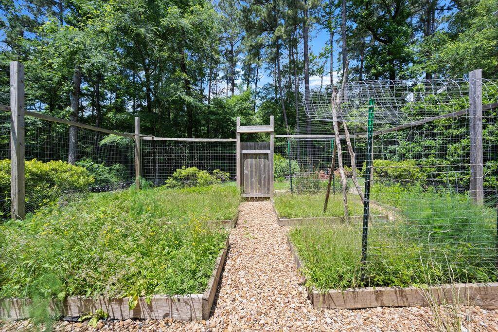 A true fenced garden area with a rustic wooden entrance gate, complete with raised beds, trellis areas for vining vegetables, and more.