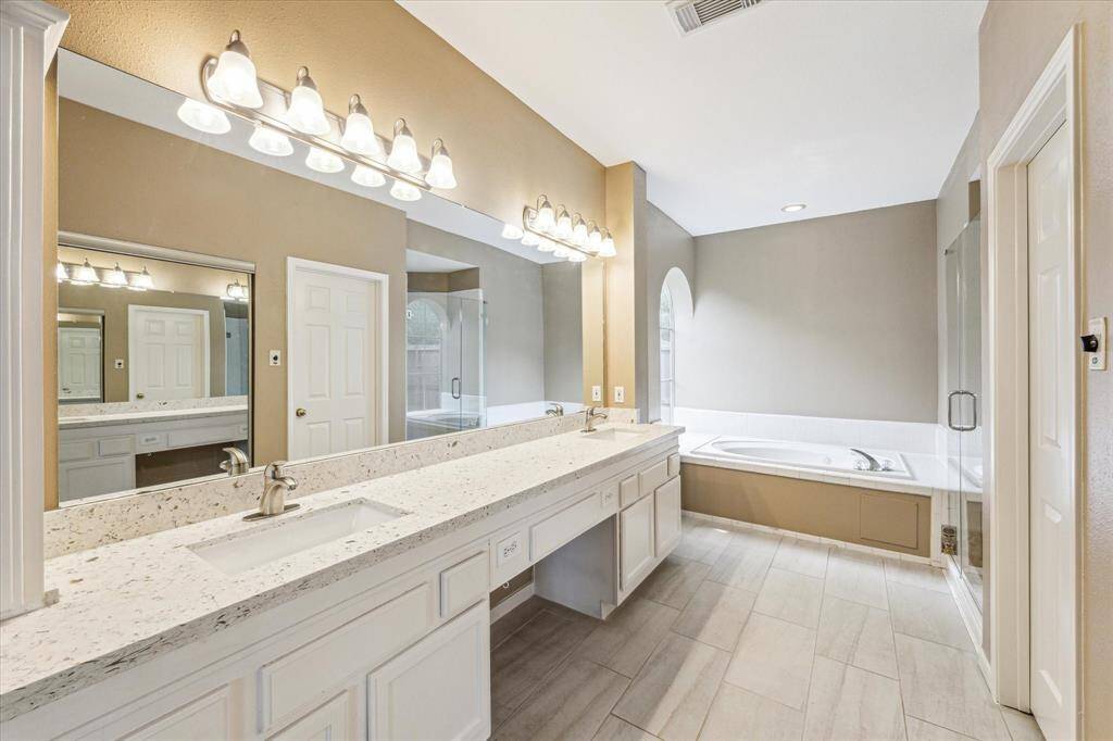 Ample countertop space with a vanity area, tub and separate shower.
