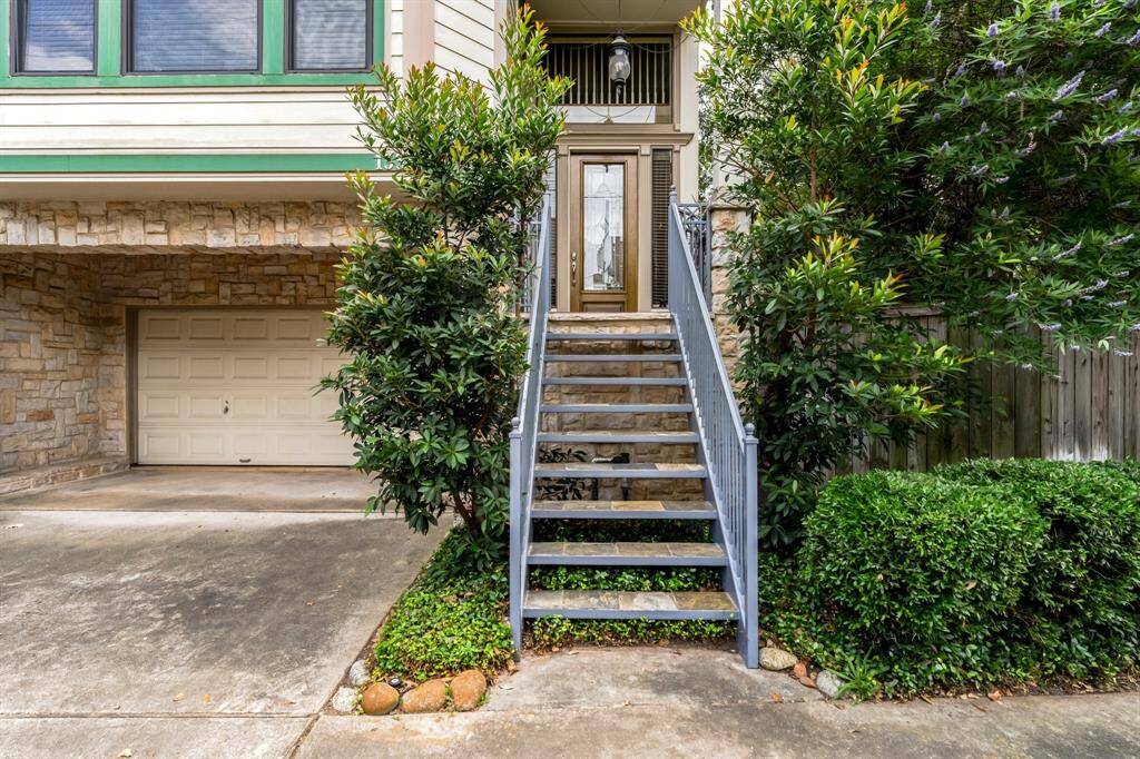 Front elevation with stairs leading to entry, framed by established landscaping.