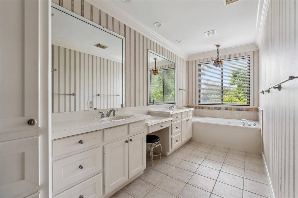 Primary bath with double vanities, soaking tub, and separate walk-in shower with tile surround.