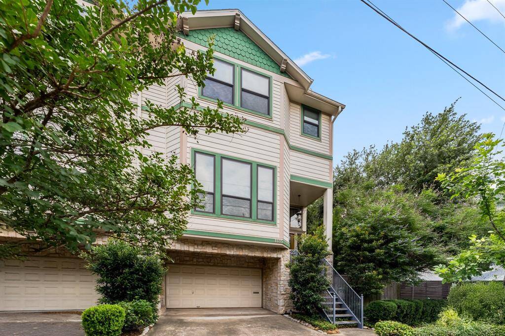 Lush greenery and tree canopy frame the front of the home, offering curb appeal and privacy.
