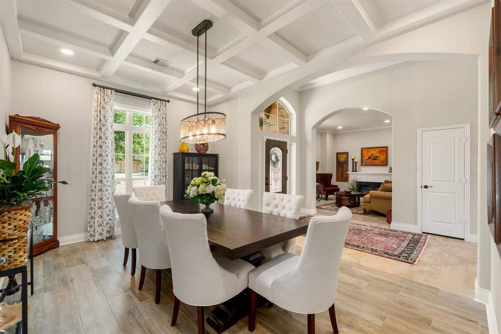 Step into elegance through this stunning entryway featuring soaring ceilings, tray detailing, and abundant natural light streaming through the decorative glass front door. The spacious foyer is anchored by sleek tile flooring adorned with modern decor. A built-in office nook adds functionality, while arched doorways lead seamlessly into the heart of the home.