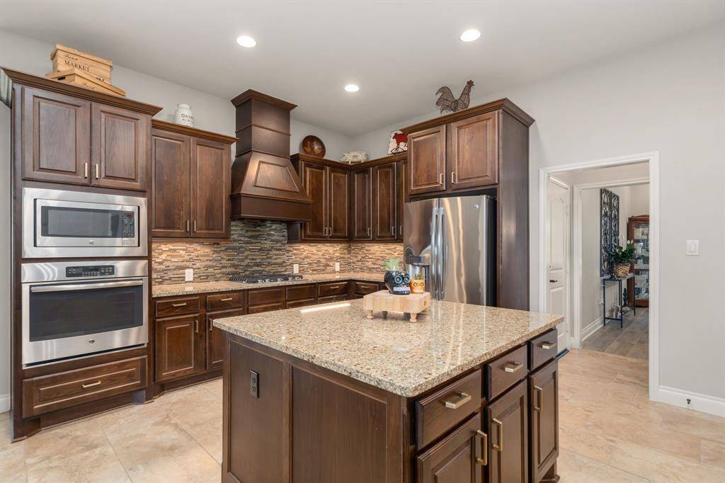Another shot of your beautiful kitchen showcasing the gas range cooktop, tile backsplash, dark stained cabinets and plenty of outlets for all your kitchen gadget needs.