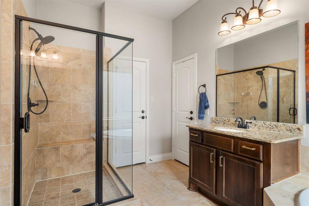 Secondary bedroom features tile flooring, neutral paint, dark stained ceiling fan with lighting and a large window with privacy blinds.