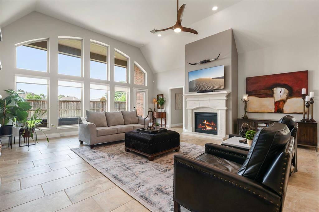 This living room is more like a GREAT room featuring a stunning fireplace with mantel detailing, custom neutral paint, soaring high ceiling, recessed lighting, custom ceiling fan, and an amazing wall of windows providing a lovely view of your backyard to keep an eye out on the kids or pets playing.