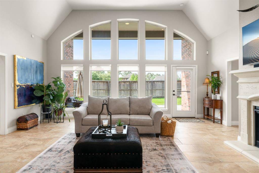 Bask in natural light in this beautifully designed living room featuring a dramatic wall of arched windows, elegant neutral tones and seamless access to the backyard through a full glass door.