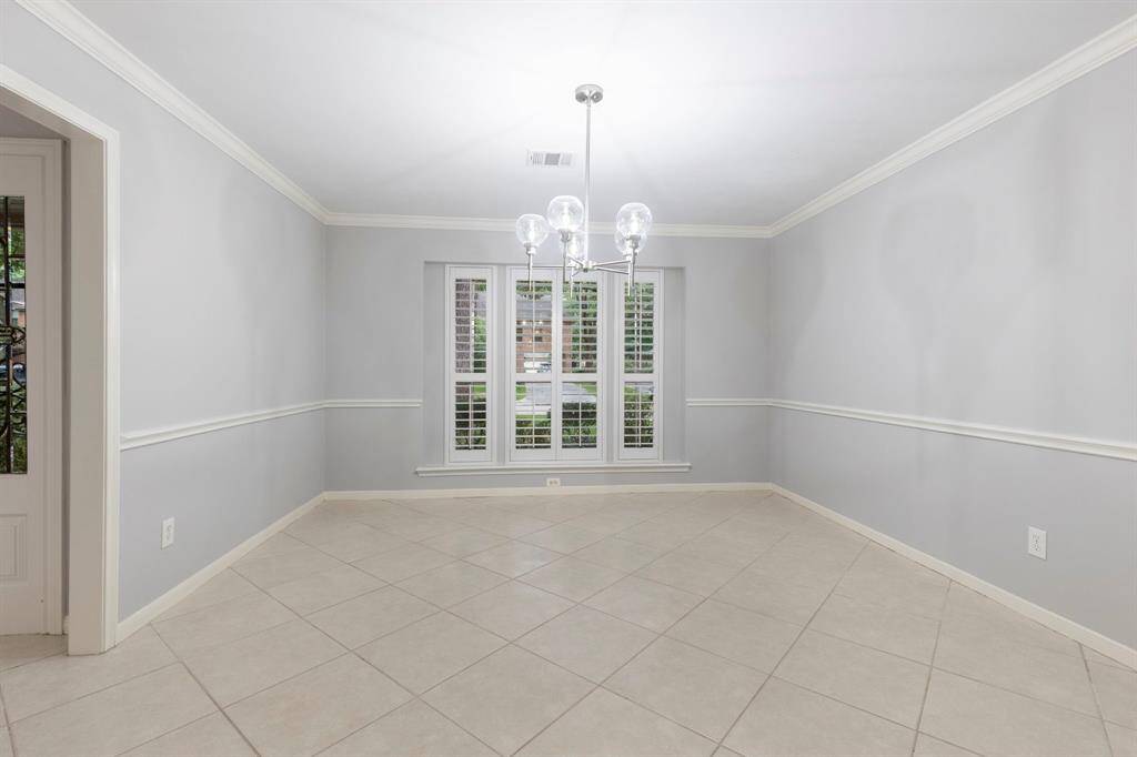 Elegant formal dining with plantation shutters, crown molding and updated chandelier.