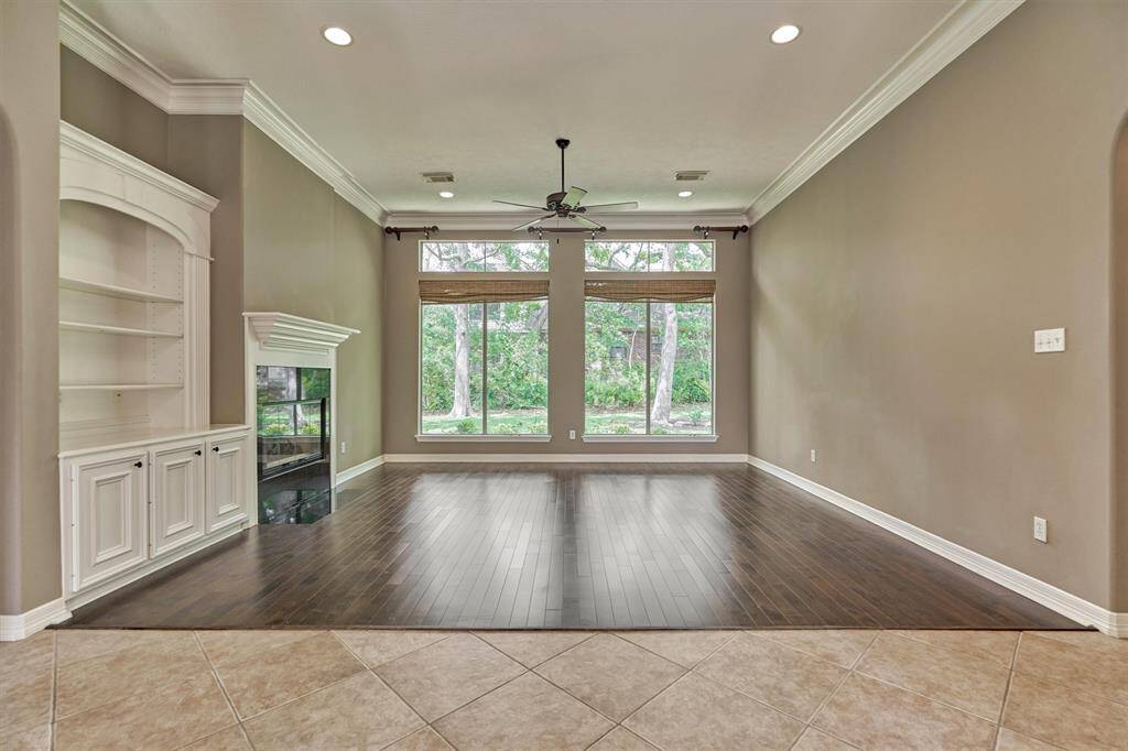 The formal living room offers rich wood flooring, custom built-ins and a wall of windows allowing pretty views of the beautiful outdoors.