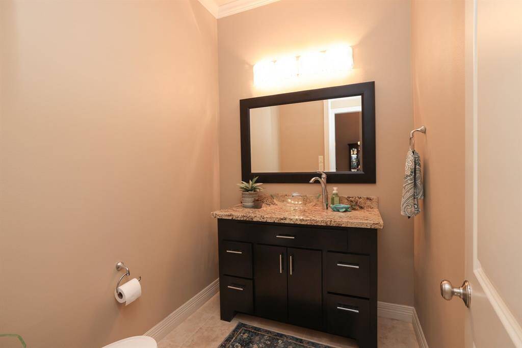 This bathroom features a modern vanity with a granite countertop, a large mirror, and stylish lighting. The neutral walls and sleek cabinetry provide a clean, contemporary feel.