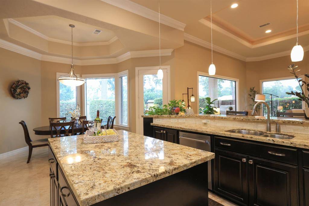 Discover a spacious kitchen featuring elegant pendant lighting and a sophisticated tray ceiling. Enjoy abundant natural light and privacy, thanks to large windows and mature hedges surrounding the home.