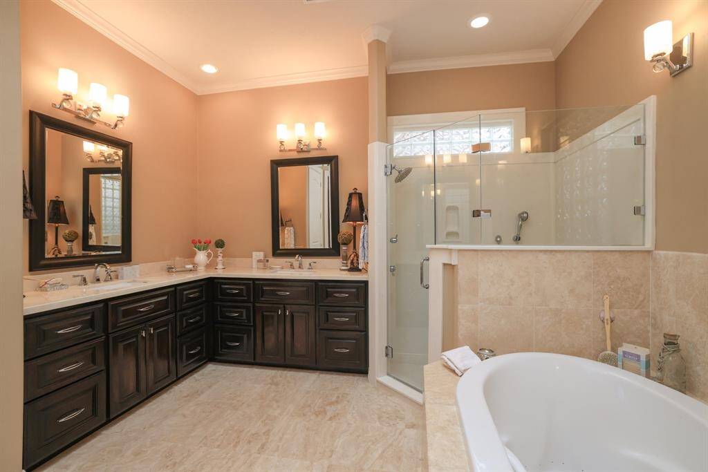 The elegant bathroom boasts a spacious double vanity with undermount sinks, stylish wood-framed mirrors, and modern lighting.