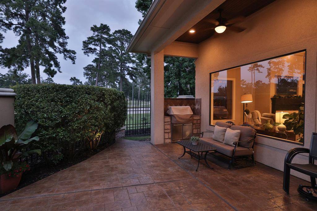 Just around the corner with access to the bak door is a cozy 2nd seating area with a built-in grill, and a well-maintained stamped concrete floor. The space is bordered by lush greenery and has large windows, offering a seamless connection between indoor and outdoor living. Just a perfect area for entertainment!