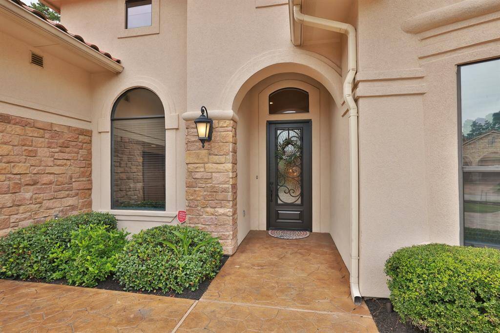 Charming entrance with an elegant black door featuring wrought iron detailing, surrounded by stone and stucco accents. Welcome to 16114 Villa Fontana Way!
