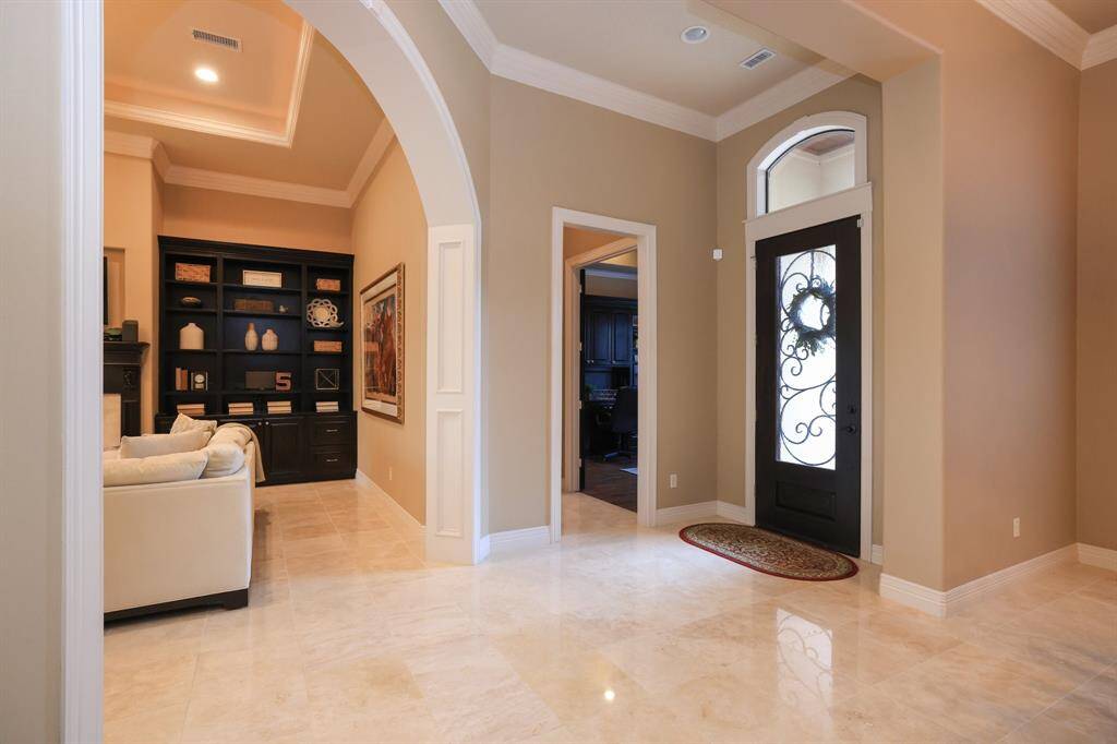 This sophisticated entryway has  a decorative front door.  Just to the right of the entry is a home office and half bath. The neutral tones and high ceiling create an inviting and spacious feel.