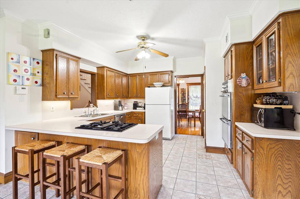 Another perspective of the Kitchen highlights the breakfast bar, seamless flow to the Dining Room, and a peek through to the spacious Living Room/Den.