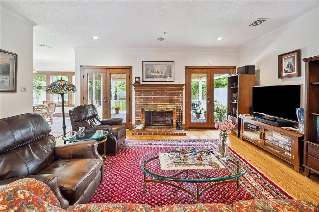 The stunning Living Room/Den boasts double French doors, a handsome fireplace, abundant natural light, and beautiful hardwood floors.