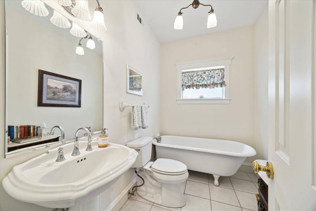 The spacious downstairs Full Bath showcases a clawfoot tub, a pedestal sink, and natural light.