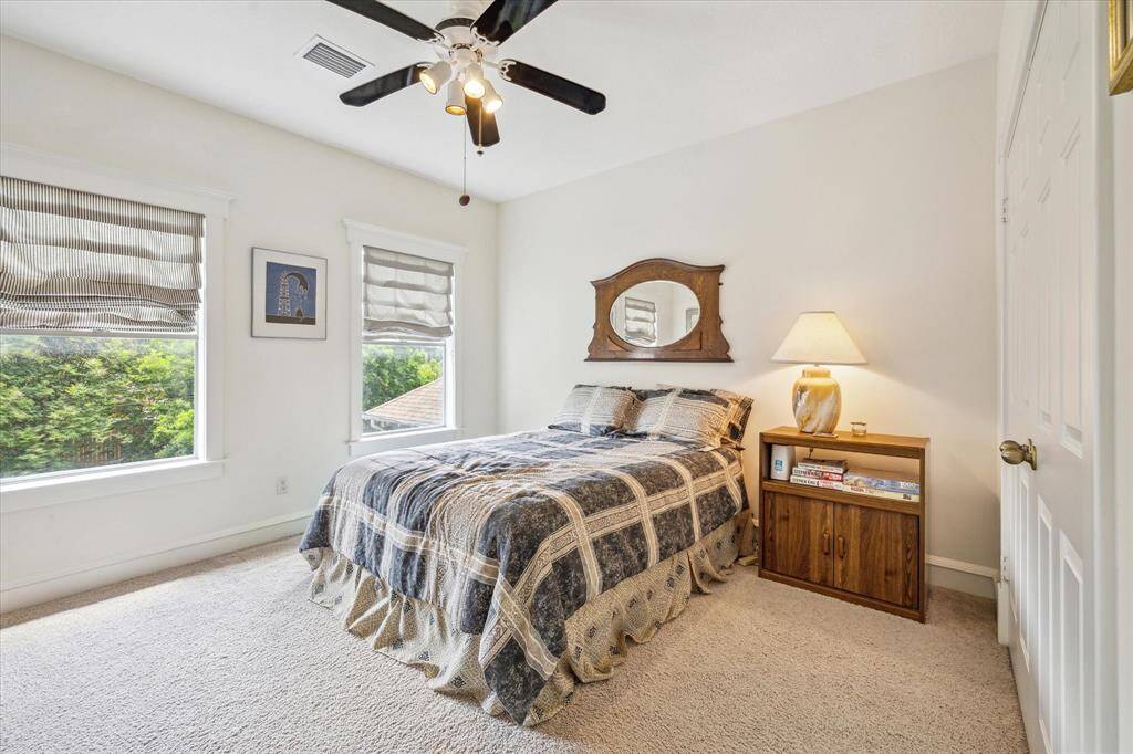 The upstairs secondary bedroom features double windows, a sizable closet, and a serene atmosphere enhanced by views of tranquil trees and nature in the backyard.