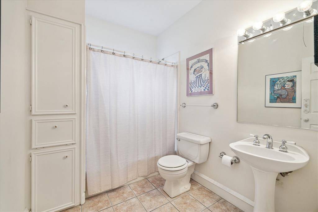The upstairs secondary bath is spacious, filled with natural light, and offers ample storage, including a laundry hamper cabinet.