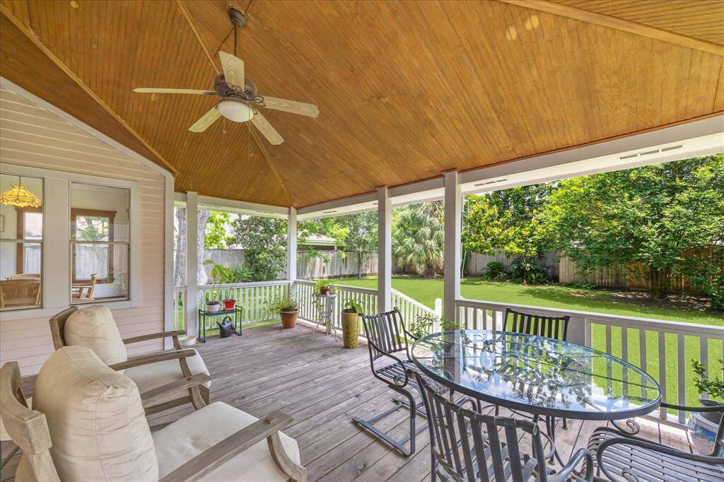 Preview of the fully covered back porch, complete with a ceiling fan, offers a serene view of the gorgeous yard and lush trees, creating an ideal setting for relaxation and enjoyment.