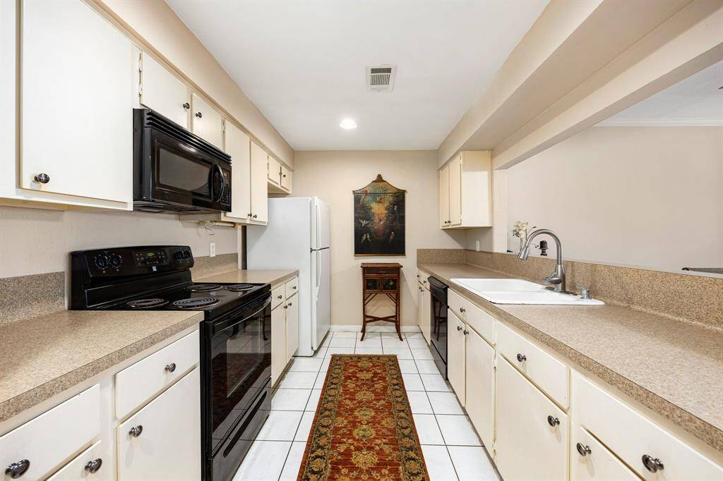 A cook’s delight, this galley-style kitchen boasts abundant counter space, ample cabinetry, and matching appliances—all conveniently situated with a pass-through to the living area for effortless entertaining.