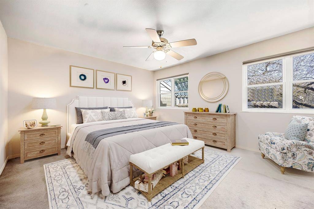 Secondary bedroom features plush carpet, custom paint, dark stained ceiling fan with lighting and a large window with plenty of natural light. *Virtually Staged