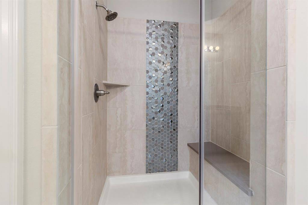 The beautifully tiled shower has an exquisite accent in the center with a large bench.