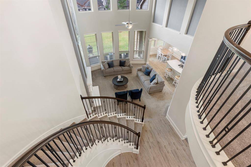 The breathtaking view from the top of the spiral staircase showcases the floor to ceiling windows looking into the backyard.