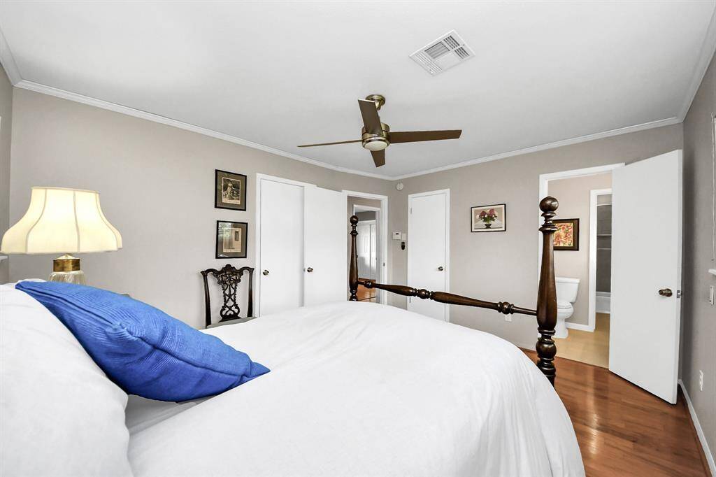 The master bedroom offers a serene view of the beautifully landscaped backyard, featuring a stunning Vitex tree with vibrant purple foliage.