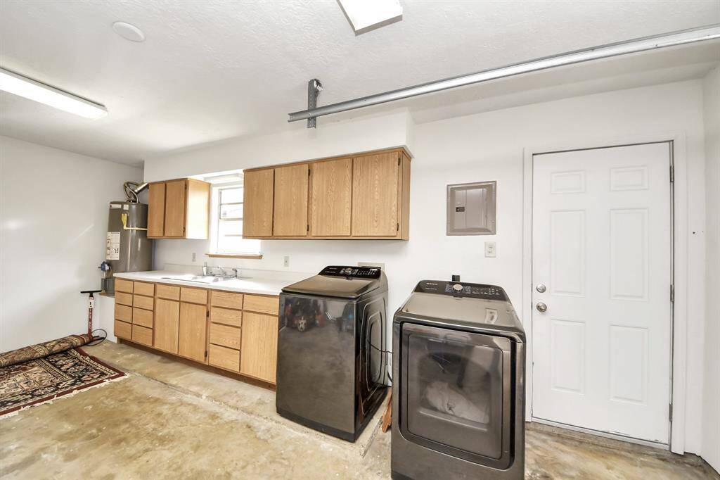 This garage laundry area features a full sink, ample storage cabinets, and a picturesque view of the backyard.