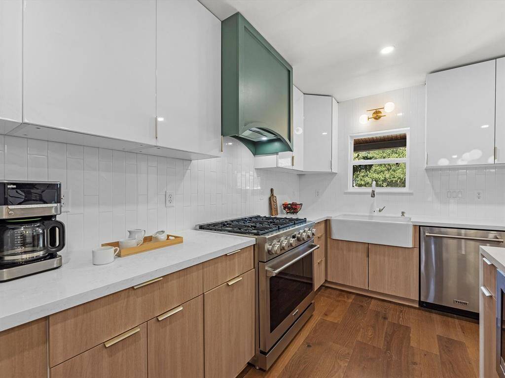 Featuring designer gold cabinet hardware, a tiled backsplash, and extensive storage space throughout.