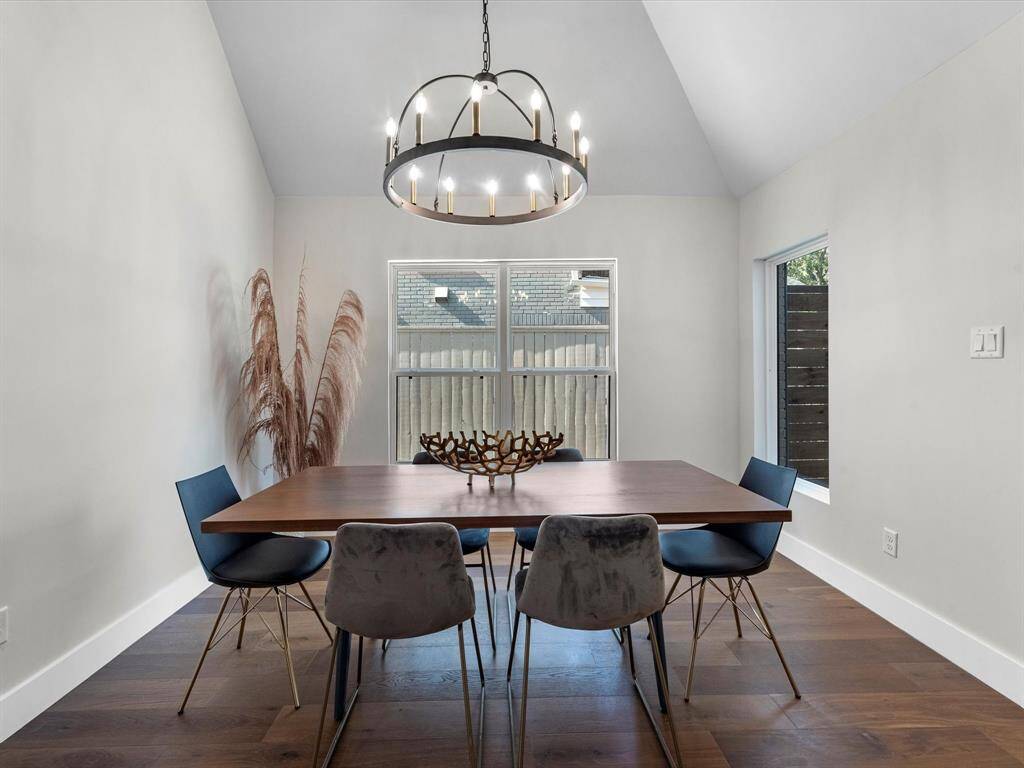 Spacious dining room with high vaulted ceilings, large windows, and an extravagant designer chandelier for a luxurious touch.