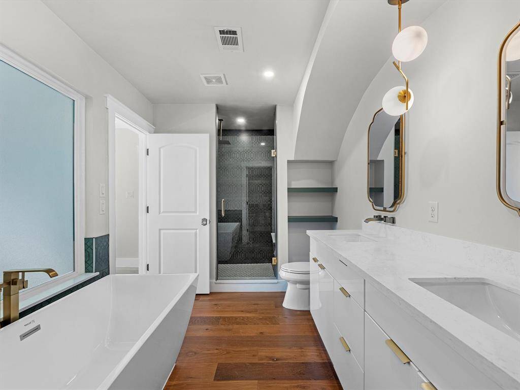 The primary bathroom features a frosted privacy window that allows abundant natural light while maintaining seclusion, along with additional built-in shelving for decor or extra storage.