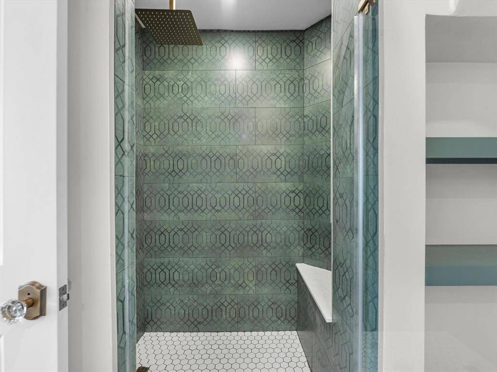 The floor-to-ceiling tiled shower features a built-in seating area, combining luxury and functionality for a spa-like experience.