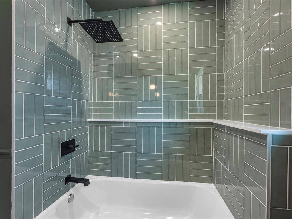 The hallway tub and shower showcases designer glass tiles in a modern layout, complemented by built-in shelving for functional and stylish storage.