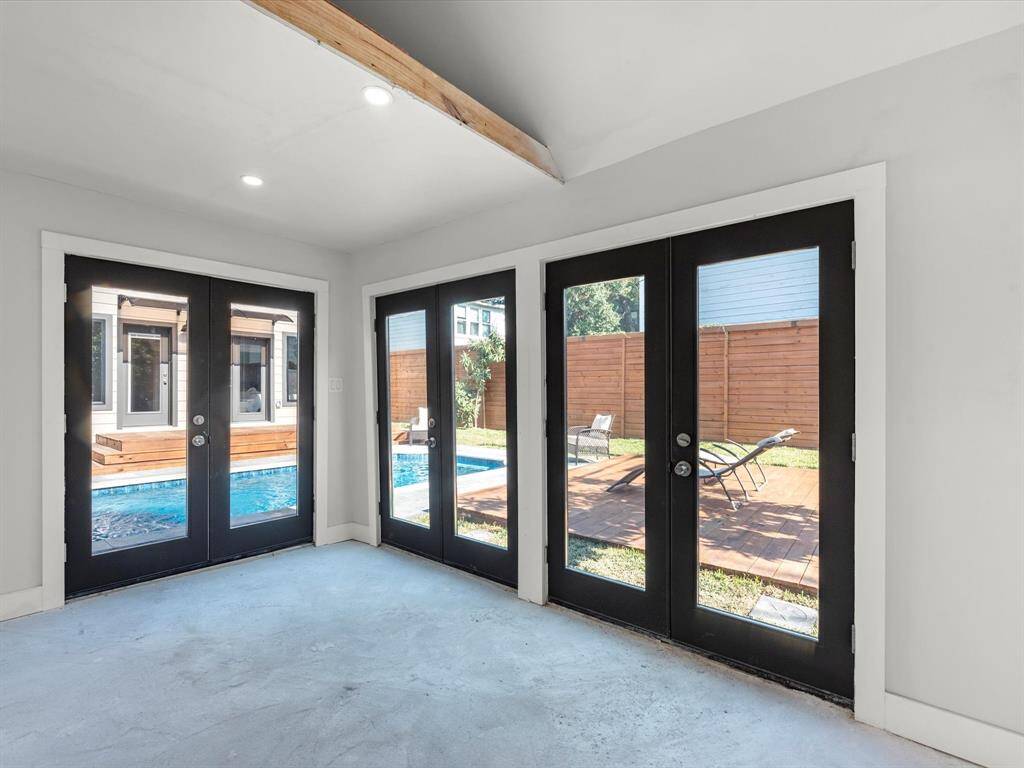 The pool house flex space features expansive double doors opening to the backyard and pool, providing a versatile area perfect for entertaining, a home gym, or a guest retreat.