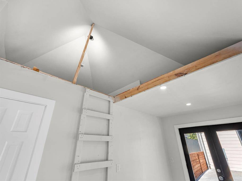 The pool house features a loft-style storage area, accessible by a built-in ladder, offering additional space for organizing items while maintaining a sleek, functional design.