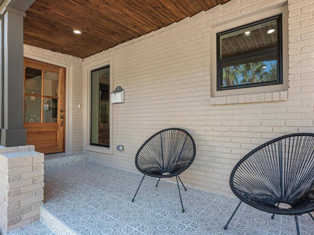 Highlighting a stunning Red Mahogany wood door, sleek black-frame windows, and a spacious seating area for relaxation.