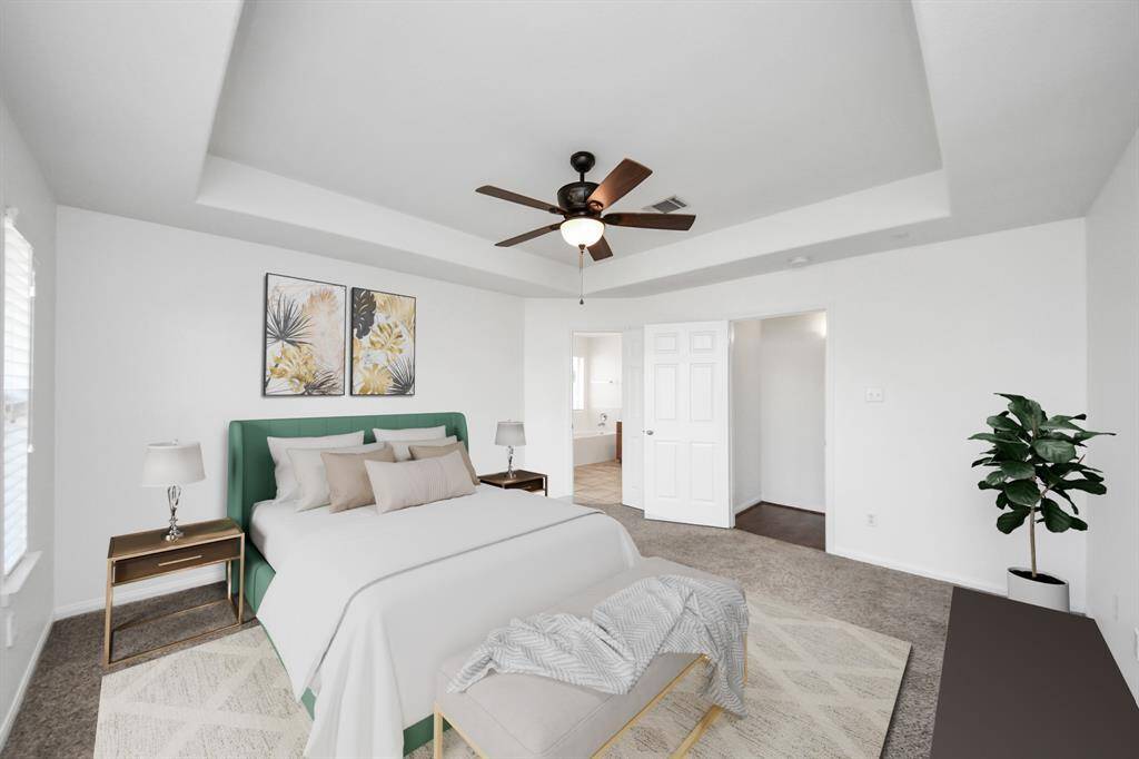 Spacious primary suite with tray ceiling, ceiling fan, and direct access to a luxurious en-suite bath. (virtually staged)