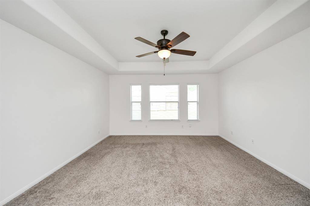 Bright and expansive owner’s retreat with plush carpet and triple windows for natural light.