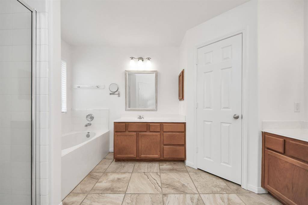 Primary bath with soaking tub, separate shower, and generous vanity space.
