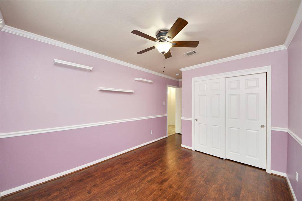 Spacious secondary bedroom with rich wood-look flooring and stylish ceiling fan.